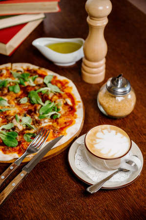 Mushroom pizza with addition mozzarella cheese and herbs on a wooden table, top view. Italian fast food. Delicious hot pizza sliced and served on wooden platter with ingredientsの写真素材