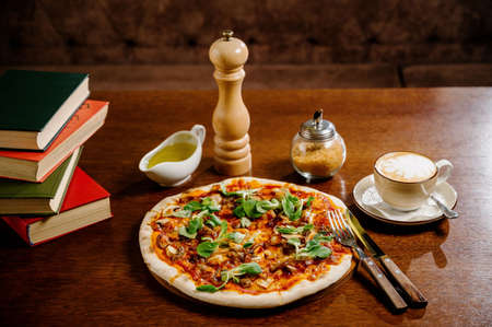 Mushroom pizza with addition mozzarella cheese and herbs on a wooden table, top view. Italian fast food. Delicious hot pizza sliced and served on wooden platter with ingredientsの写真素材