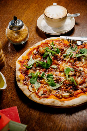 Mushroom pizza with addition mozzarella cheese and herbs on a wooden table, top view. Italian fast food. Delicious hot pizza sliced and served on wooden platter with ingredientsの写真素材