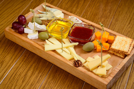 various types of cheese on wooden cutting board, top view.の写真素材