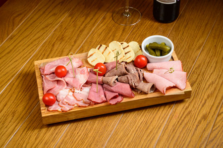 Different types of chopped sausages on a wooden board on a tableの写真素材