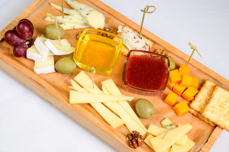 various types of cheese on wooden cutting board, top view.の写真素材