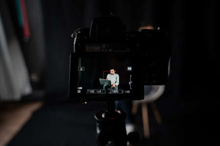 Man recording video, using digital camera in studio, successful freelancer, modern blogger, business coach making content, using professional equipmentの写真素材