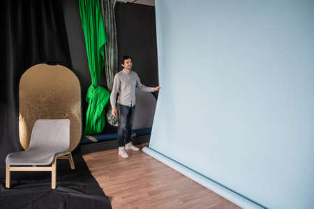 Photographer prepares for shooting in a photo studio.Man changing paper background in a photo studioの写真素材