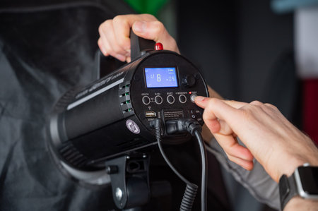 Photographer adjust softbox light intensity in studio. Man setting photographing equipment getting ready for a photo shoot.の写真素材