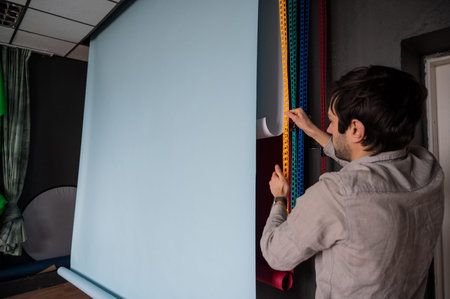 Photographer prepares for shooting in a photo studio.Man changing paper background in a photo studio