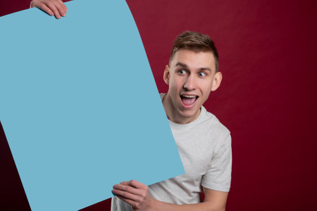 Surprised man with empty advertising banner. Man holds board for advertising. Handsome man with sign board. Space for text. Advertising. Black friday.の写真素材