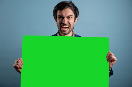 Screaming mad man holding blank poster.Screaming man holding a green poster.Angry man showing blank...