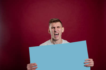 Sad young man holding blue advertising banner. Sad young man with empty advertising banner. Man holds board for advertising. Handsome man with sign board. Space for text. Advertising. Black friday.の写真素材