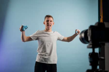 Young man tearing medical mask in studio. Removing mask, quarantine ends. Getting out of isolationの写真素材