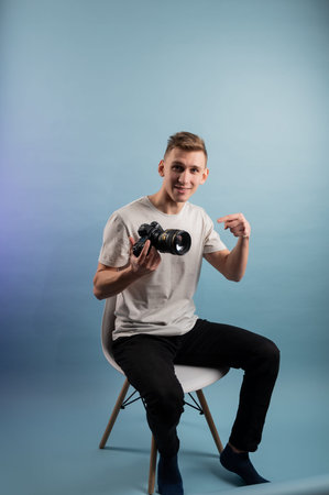 Handsome young photographer using camera on blue background.Man using a professional camera.Portrait...