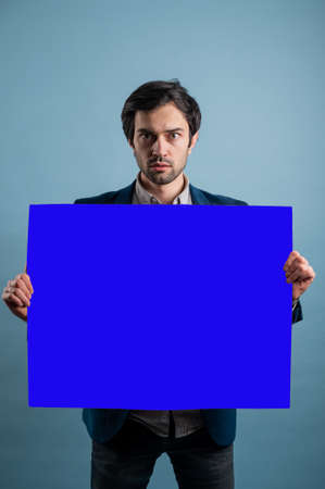Surprised man with empty advertising banner. Man holds board for advertising. Handsome man with sign board. Space for text. Advertising. Black friday.の写真素材