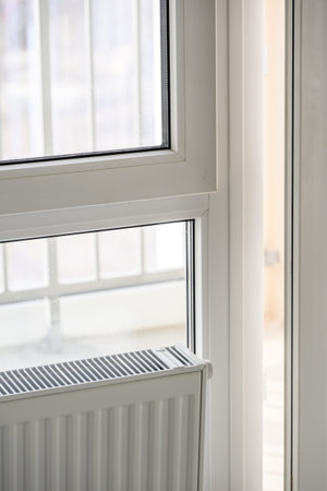 Interior view of a modern window overlooking an urban apartment building, with a white wall and radiator visible in the roomの写真素材