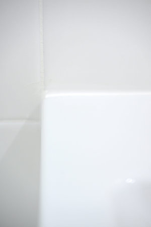 Close-up view of a white bathtub corner meeting a clean tiled wall in a modern bathroom setting with...
