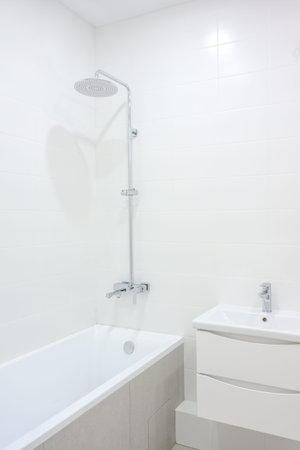 Contemporary bathroom featuring a sleek showerhead above a white bathtub, complemented by a...