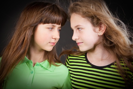 Portrait of two young beautiful girls in studio a dark backgroundの写真素材