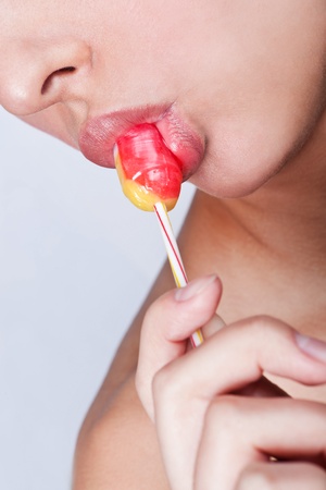 Woman licking a red shiny lollipopの写真素材