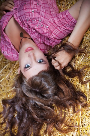 Portrait of long-haired brunette girl in pink on background of haystackの写真素材