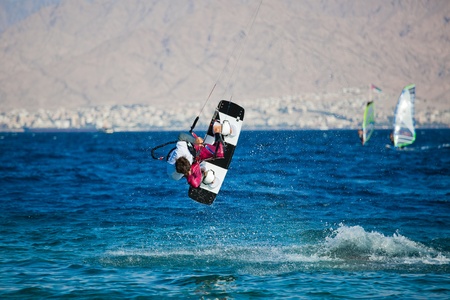 Kite surfing on the sea. The beautiful suntanned young guy goes for a drive on a board by the seaの写真素材