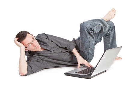 Young man lying on the floor working on his laptopの写真素材