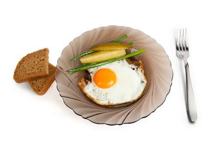 Breakfast Fried eggs on a glass plate, with a marinaded cucumber, fresh onions and rye breadの写真素材