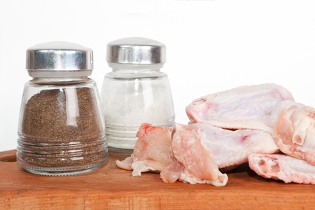 Raw chicken on plate with salt and pepperの写真素材