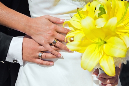 Bride and groom hands with wedding rings and bouquetの写真素材