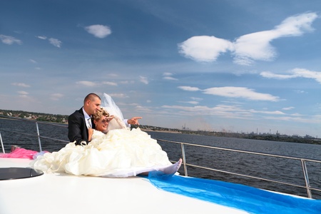 Happy newly-married couple floats on the yacht and looks afarの写真素材
