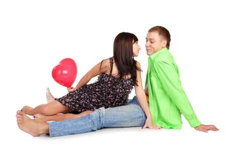 The beautiful guy both the nice girl sit also the girl holds a red balloon-heartの写真素材