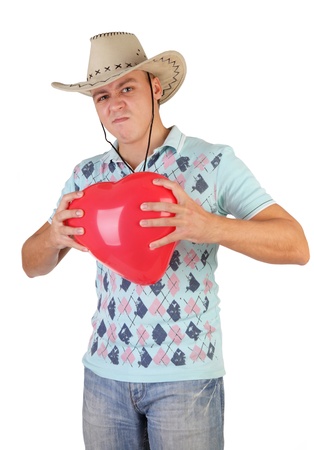 young guy holding a red heart-shaped balloon on a white backgroundの写真素材