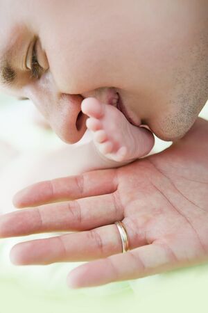 Close up of the father of baby kissing a legの写真素材