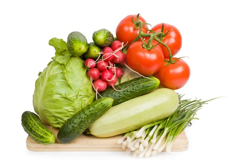 fresh vegetables on wooden chopping board isolated over white background の写真素材