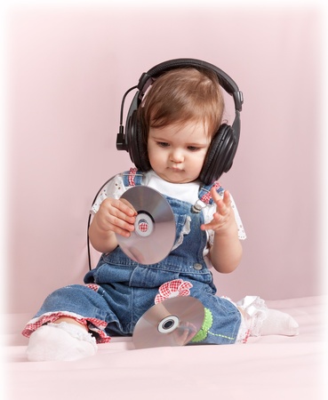 child with CD discs sits and listens to music in ear-phonesの写真素材