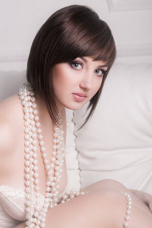 Tempting woman in white lingerie with beads in studioの写真素材