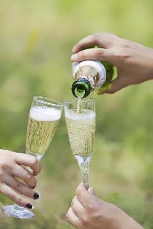 Champagne pour with two glasses in handsの写真素材