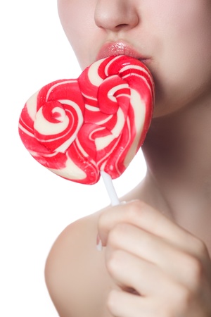 candy red heart on the lips of a girl close up isolated on a white backgroundの写真素材