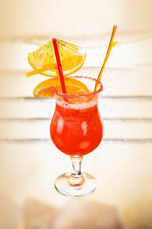 Orange alcohol cocktail with fruit slices on a glass tableの写真素材