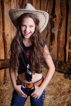 beautiful cowgirl style model posing on farmland near hayの写真素材