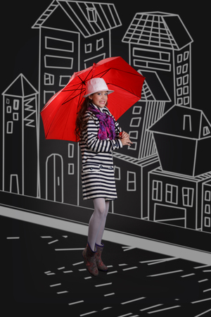 Beautiful fashionable young girl with red umbrella in the streetの写真素材