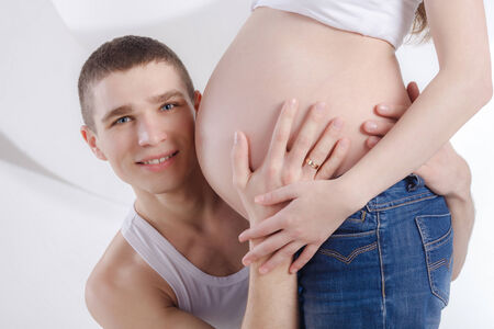 Husband listening to his wife s bellyの写真素材