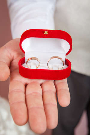 Close up mans palms holding wedding ringsの写真素材