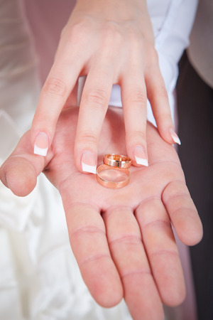 Bride and groom showing their wedding rings on their palmsの写真素材