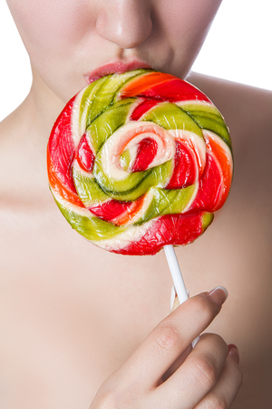 multi-coloured candy on the lips of a girl close up isolated on a white backgroundの写真素材