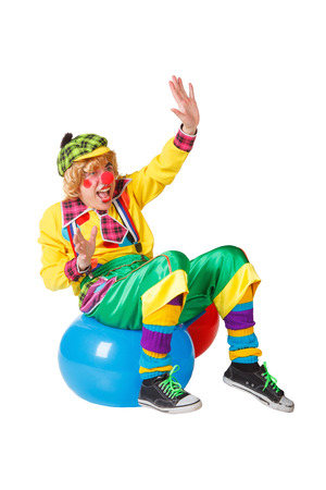 Funny clown sits on blue ball isolated on white backgroundの写真素材
