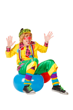 Funny clown sits on blue ball isolated on white backgroundの写真素材