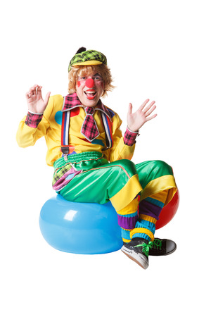 Funny clown sits on blue ball isolated on white backgroundの写真素材
