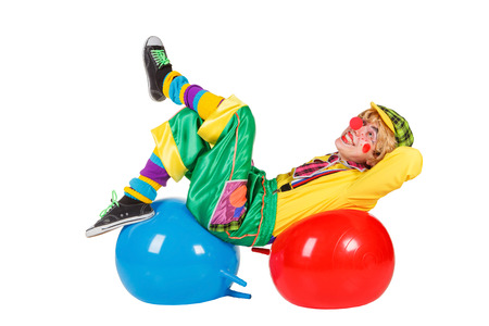 Funny clown lies on balls isolated on white backgroundの写真素材