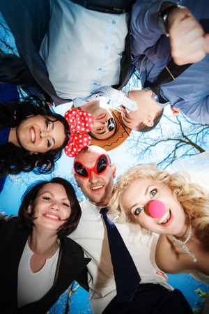 Group of happy young people in circle at blue sky background have fun and smileの写真素材