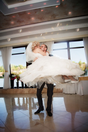 Kiss and dance young bride and groom in banqueting hallの写真素材