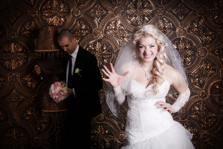 happy groom and the charming bride with a bouquet from roses in studio on a brown backgroundの写真素材